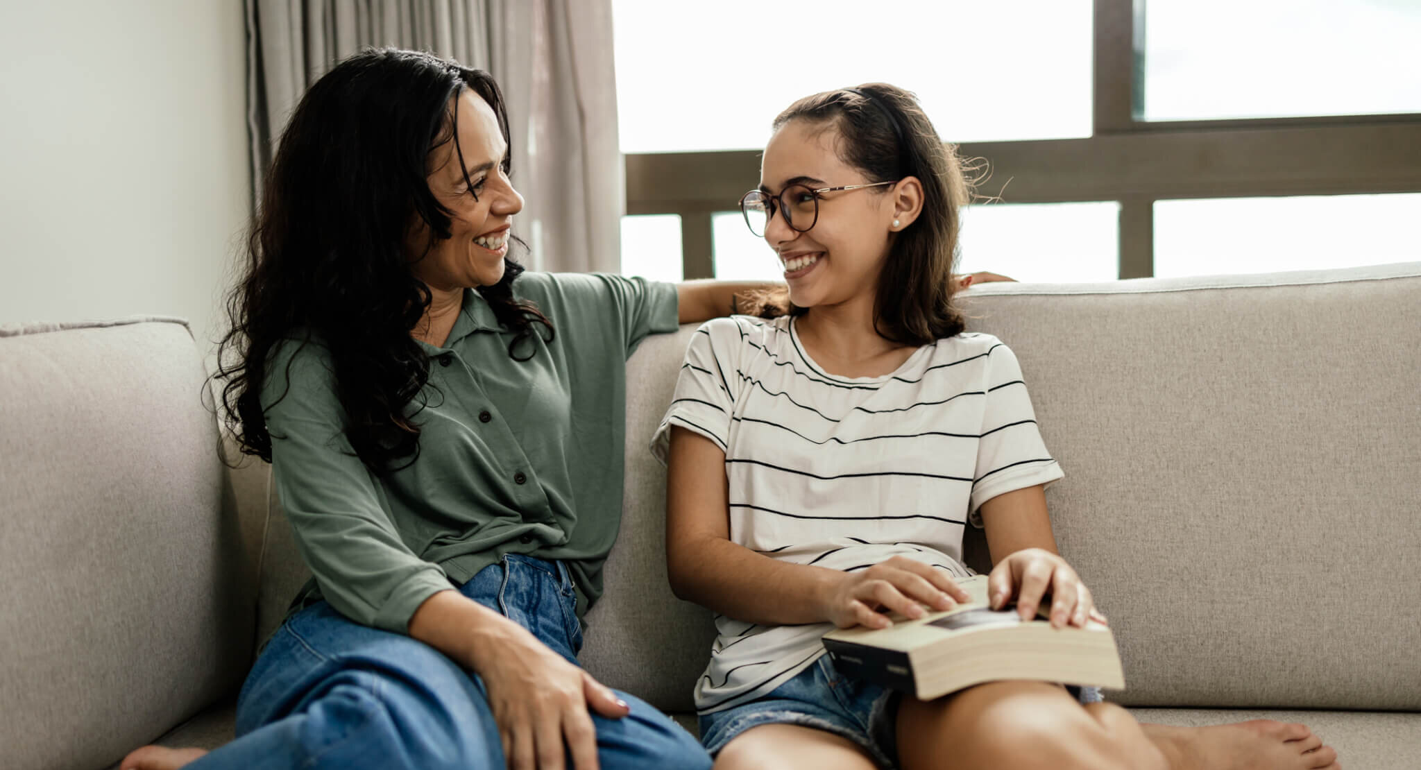 A mother and her daughter look at each other while laughing.