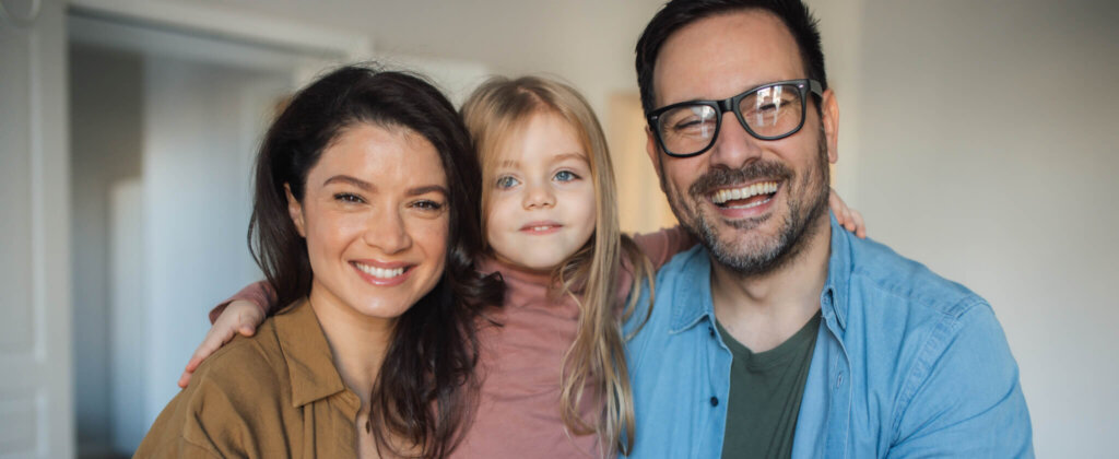 Portrait of happy parents and their daughter embracing and enjoying a weekend at home.