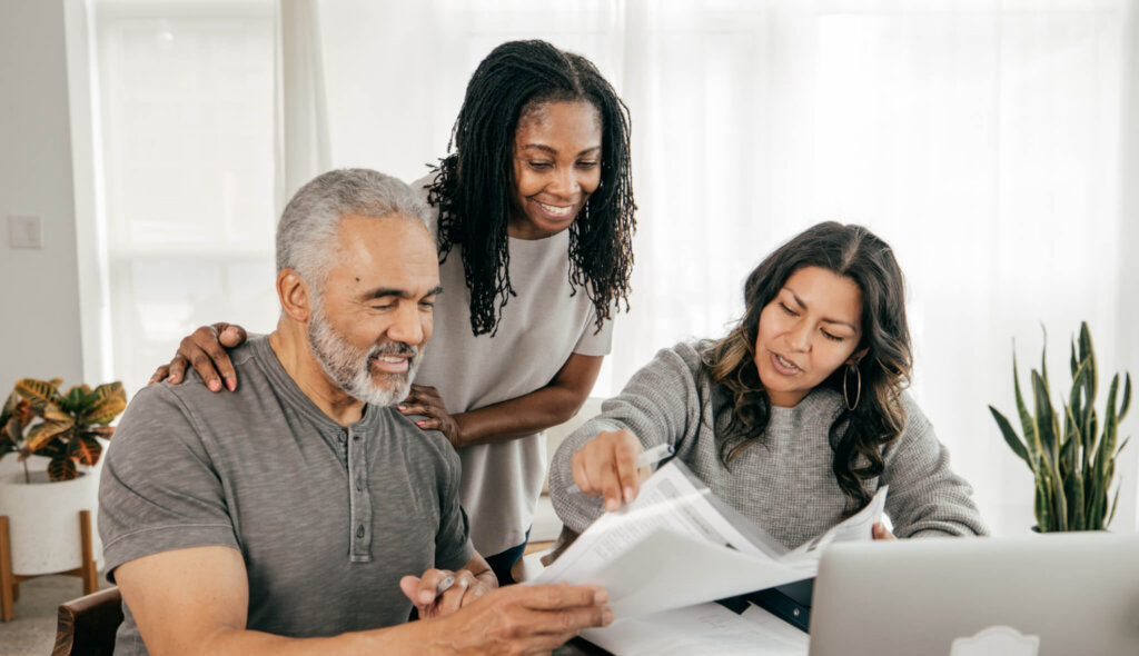 Three adults discuss estate planning while looking at a laptop.