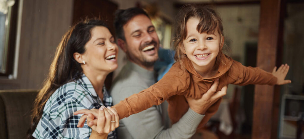 Carefree parents have fun while playing with their small daughter at home.