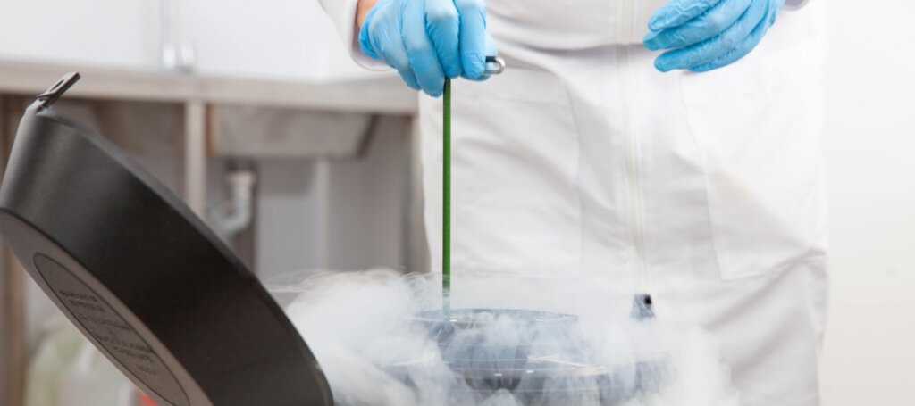 A medical professional handles a liquid nitrogen cryogenic tank.