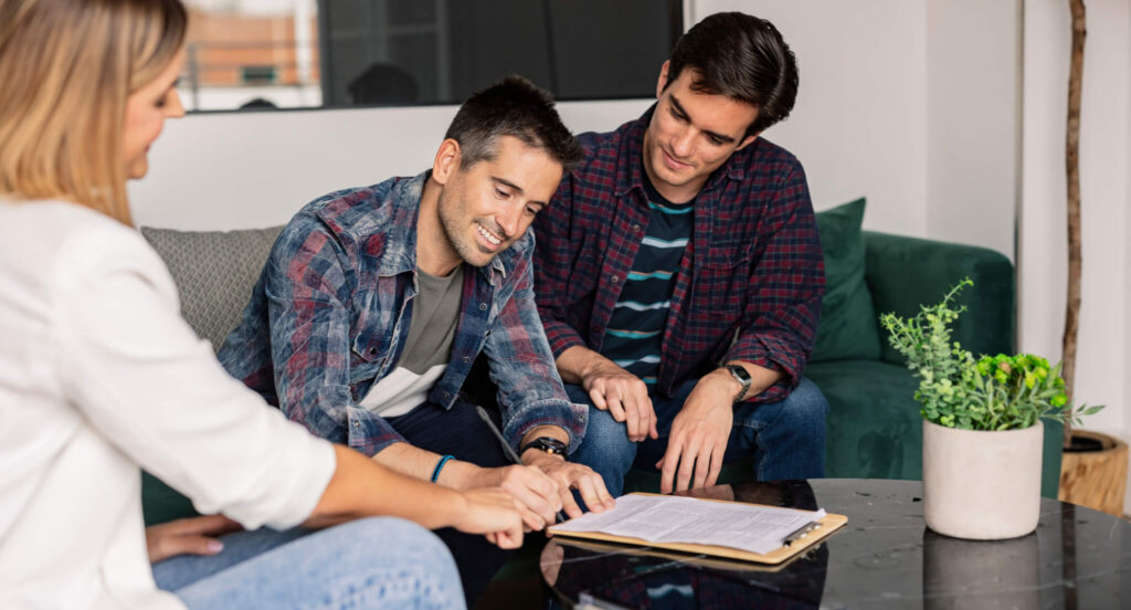 Gay intended parents sign paperwork with a friend donating eggs.