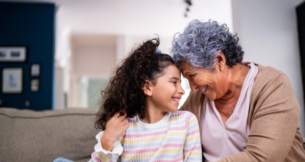 A grandparent holds her granddaughter on the couch.