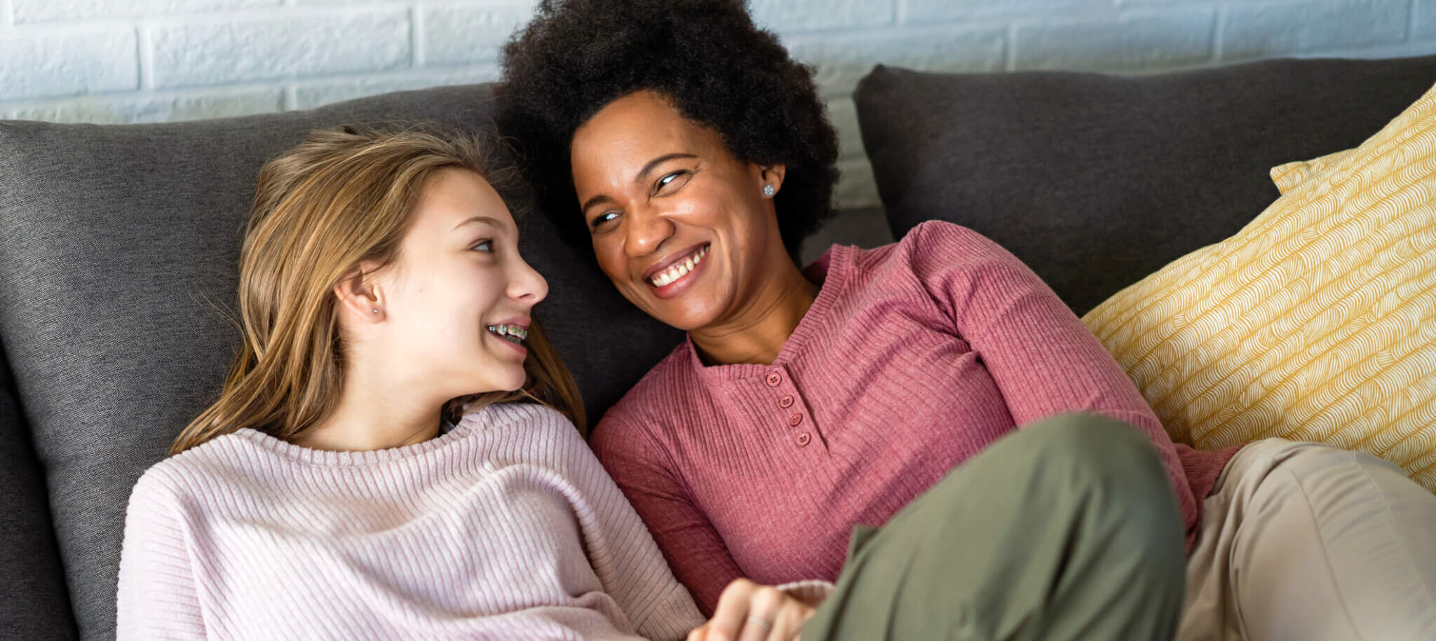 A foster care parent and foster teenager smile together.